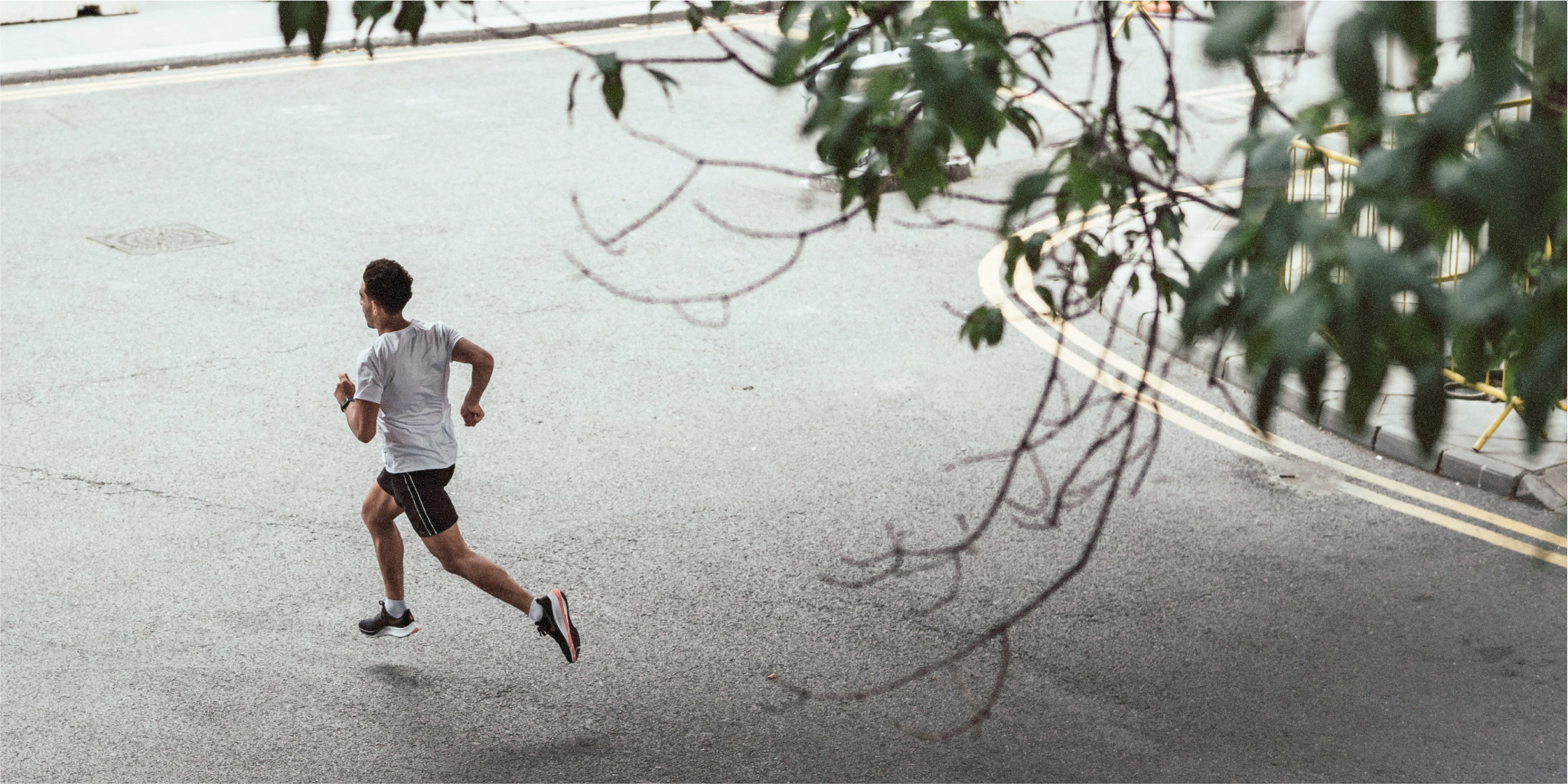 Ein Mann joggt auf einer Stadtstraße mit natürlichen Elementen.